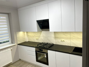 Кухня із білими фасадами та чорною стільницею